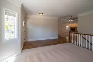 Unfurnished room with baseboards, a ceiling fan, wood finished floors, crown molding, and a stone fireplace