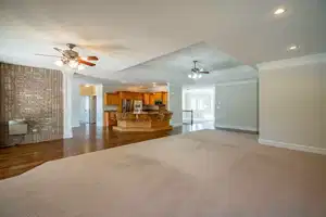 Unfurnished living room with recessed lighting, a ceiling fan, baseboards, ornamental molding, and a tray ceiling