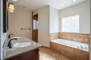 Bathroom with a bath, double vanity, a sink, and visible vents