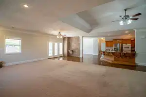 Unfurnished living room featuring a textured ceiling, a healthy amount of sunlight, dark carpet, and crown molding