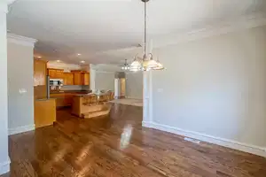 Kitchen featuring dark wood-style floors, stainless steel microwave, ornamental molding, and a kitchen bar