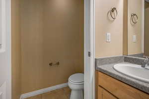 Bathroom with toilet, tile patterned flooring, vanity, and baseboards