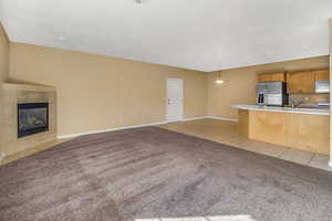 Living room with light tile patterned floors, baseboards, a tile fireplace, and light colored carpet