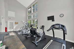 Exercise room with high vaulted ceiling and baseboards