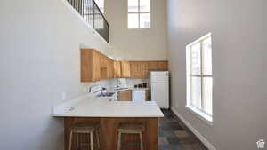 Club house Kitchen with light countertops, a sink, white appliances, a peninsula, and baseboards