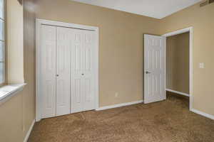 Unfurnished bedroom with a closet, carpet flooring, visible vents, and baseboards