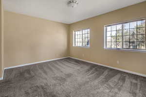 Carpeted spare room featuring baseboards