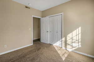 Unfurnished bedroom with baseboards, a closet, visible vents, and carpet flooring