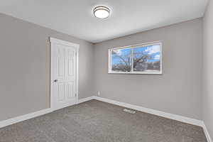 Unfurnished bedroom with dark colored carpet, visible vents, and baseboards