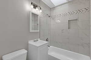 Bathroom with toilet, a skylight, shower / washtub combination, and vanity