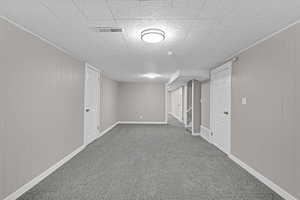 Finished basement with carpet flooring, visible vents, and baseboards