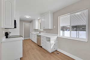 Kitchen featuring baseboards, white cabinets, light countertops, appliances with stainless steel finishes, and light wood finished floors