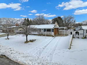 View of front of property featuring a chimney, fence, a porch, and a carport
