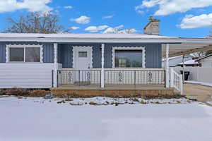 View of front of house with covered porch, a chimney, and board and batten siding