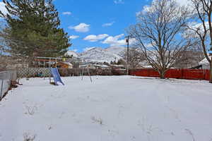 Snowy yard with a fenced backyard and a mountain view
