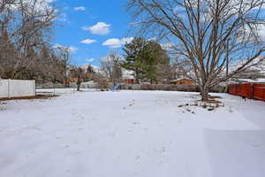 Yard layered in snow featuring fence