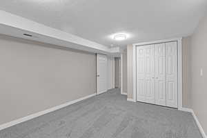 Unfurnished bedroom featuring carpet, visible vents, baseboards, and a textured ceiling