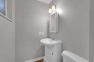 Bathroom featuring wood finished floors, vanity, toilet, and baseboards
