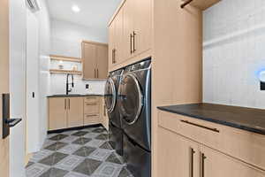 Laundry area with cabinet space, washing machine and dryer, dark tile patterned floors, a sink, and recessed lighting