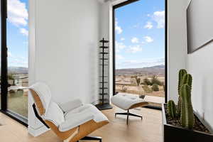 Sitting room with expansive windows, light wood finished floors, a mountain view, and a wealth of natural light