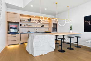 Bar featuring pendant lighting, recessed lighting, light wood-style floors, a sink, and baseboards