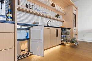 Kitchen featuring light wood-style floors, dark countertops, a sink, and open shelves