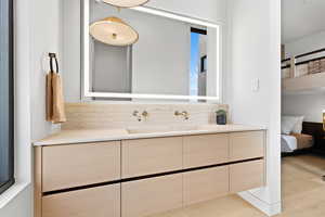 Ensuite bathroom with vanity, ensuite bath, and wood finished floors