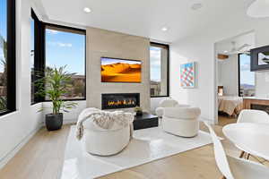 Living room featuring light wood-style floors, recessed lighting, a healthy amount of sunlight, and a tiled fireplace