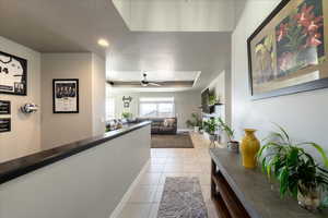 Hall with baseboards, a tray ceiling, and light tile patterned flooring