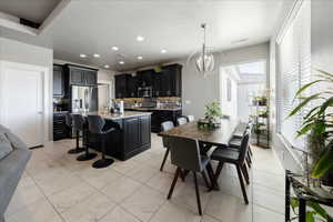 Kitchen with dark cabinets, stainless steel appliances, light countertops, tasteful backsplash, and an inviting chandelier