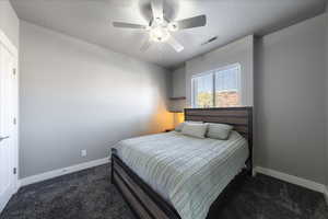 Carpeted bedroom with a ceiling fan, visible vents, and baseboards