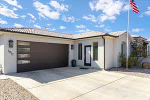 View of front of house with driveway, a tile roof, and stucco siding