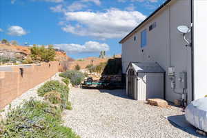 View of property exterior with a fenced backyard, a storage unit, and an outbuilding