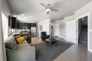 Living room with stairs, baseboards, finished concrete floors, and recessed lighting