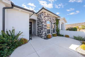 Doorway to property featuring stone siding and stucco siding