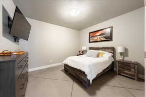 Bedroom with a textured ceiling, concrete flooring, and baseboards