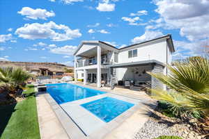 Back of house with a patio, a balcony, an in ground hot tub, fence, and a ceiling fan