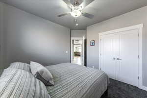 Bedroom featuring dark colored carpet, a closet, and a ceiling fan