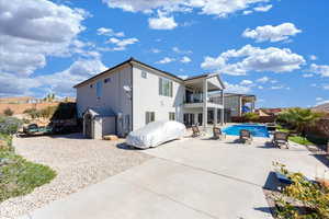 Back of house with a fenced in pool, a patio, stucco siding, a balcony, and a fenced backyard