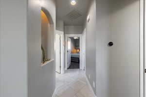 Hallway featuring arched walkways, visible vents, and baseboards