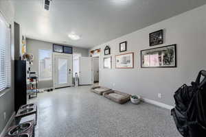 Misc room with a textured ceiling, speckled floor, visible vents, and baseboards