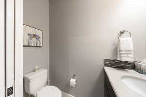 Bathroom featuring toilet, backsplash, and vanity