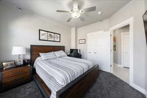 Tiled bedroom with carpet floors, ceiling fan, and baseboards