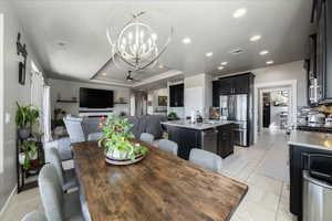 Dining room with recessed lighting, visible vents, a raised ceiling, ceiling fan with notable chandelier, and light tile patterned flooring