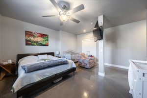 Bedroom featuring ceiling fan, a closet, baseboards, and concrete flooring