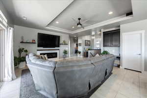 Living area featuring recessed lighting, visible vents, a ceiling fan, a raised ceiling, and a glass covered fireplace