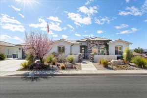 Mediterranean / spanish house featuring a fenced front yard, a tile roof, concrete driveway, stone siding, and stucco siding