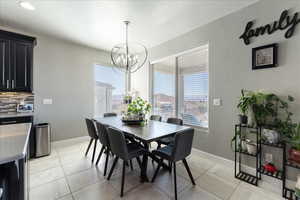 Dining space with light tile patterned floors, baseboards, and a notable chandelier