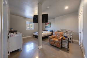 Bedroom with finished concrete floors, a textured ceiling, and baseboards