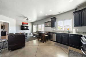 Kitchen with stainless steel appliances, finished concrete floors, open floor plan, a sink, and light stone countertops